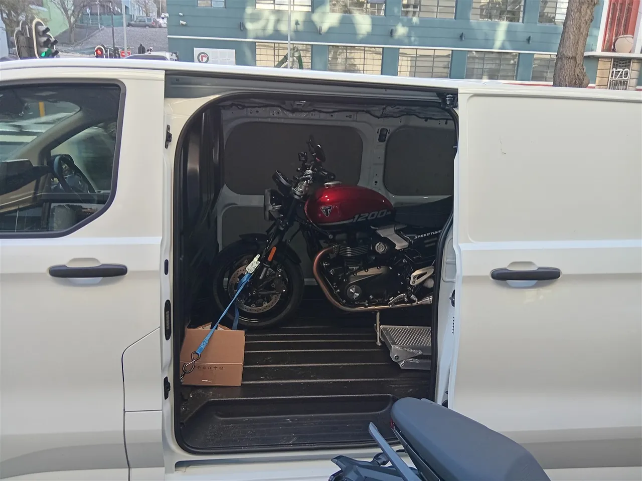 Red Triumph Speed Twin viewed through the side door of the transport van