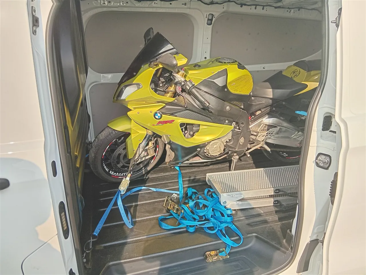 Yellow BMW S1000RR inside the transport van, with loading ramp alongside